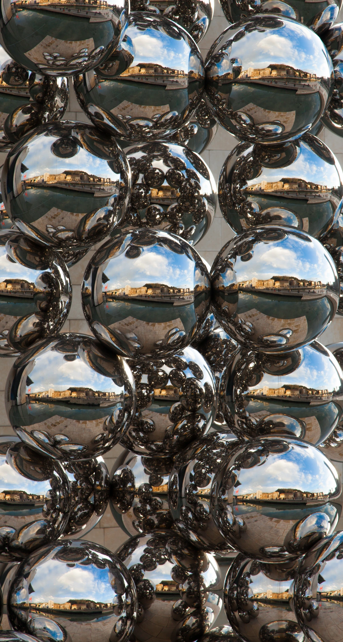 Exterior sculpture of the Guggenheim Museum Bilbao, reflecting the surrounding cityscape and sky.