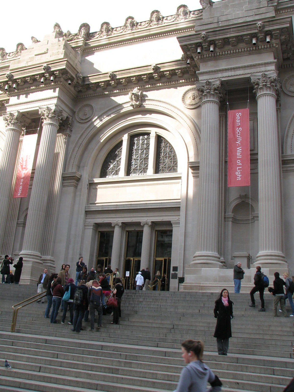 Metropolitan Museum of Art entrance with people on the steps and banners hanging from the columns.