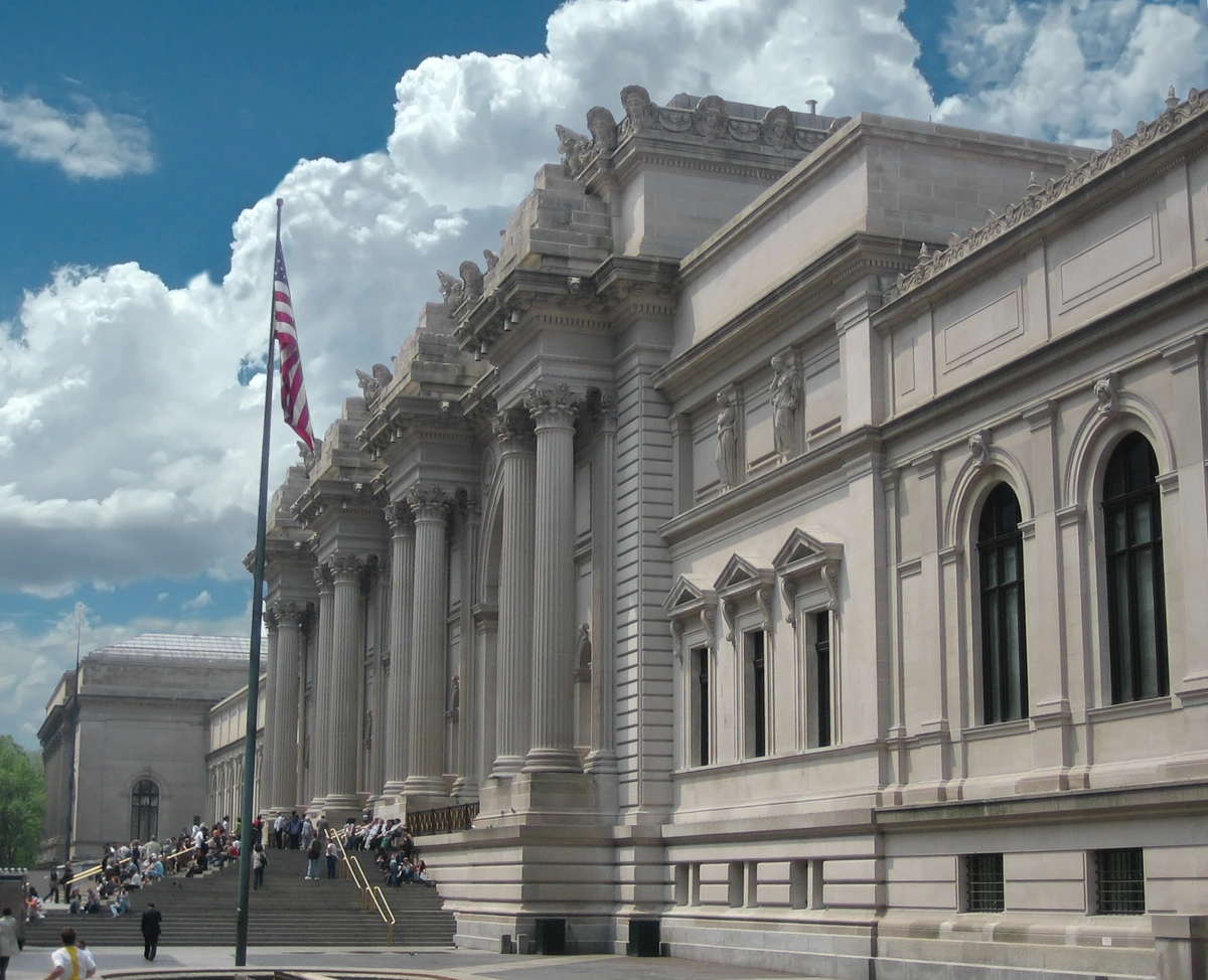 De grote ingang van het Metropolitan Museum of Art in New York City, met klassieke architectuur en de Amerikaanse vlag.