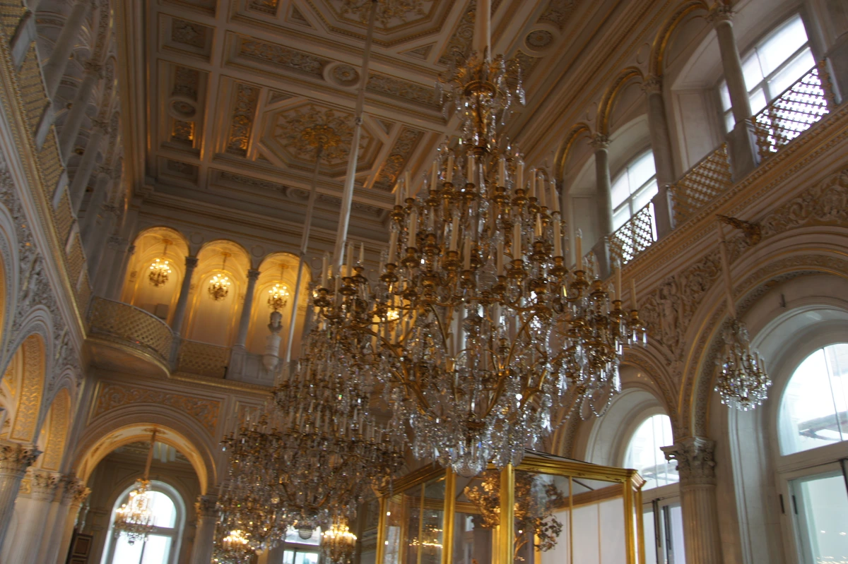 Grand interior of the Hermitage Museum in St. Petersburg, featuring ornate architecture, gilded details, and large crystal chandeliers.