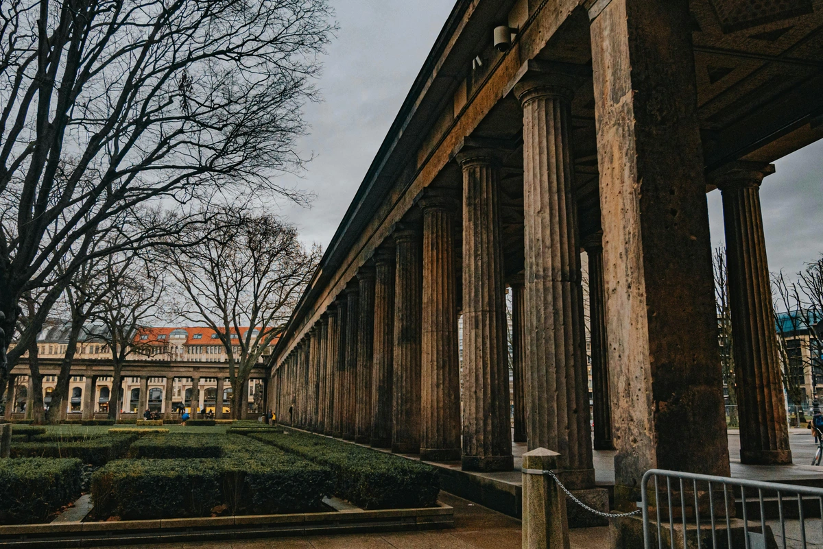 Kolonnadenhof on Museum Island in Berlin, Germany, featuring a long colonnade with classical stone columns and manicured hedges in the foreground.