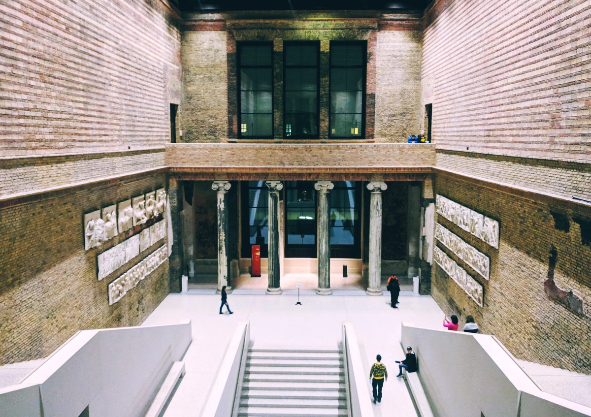 Interior view of the Neues Museum in Berlin, showcasing its grand architecture with columns, arches, and ancient artifacts.