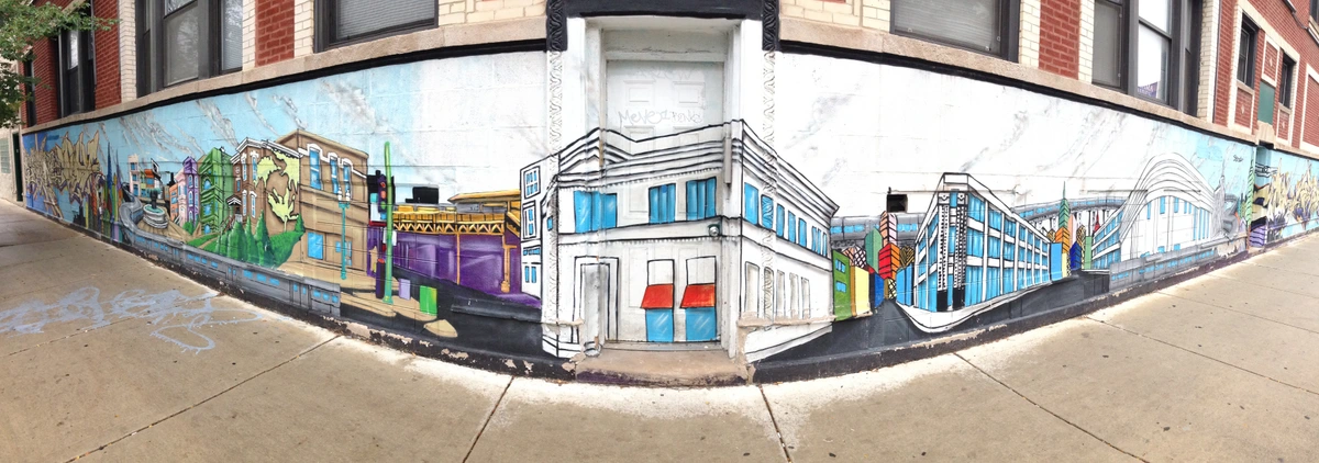 Vibrant graffiti mural depicting a cityscape with colorful buildings and abstract designs on a brick building in Chicago's Wicker Park neighborhood.