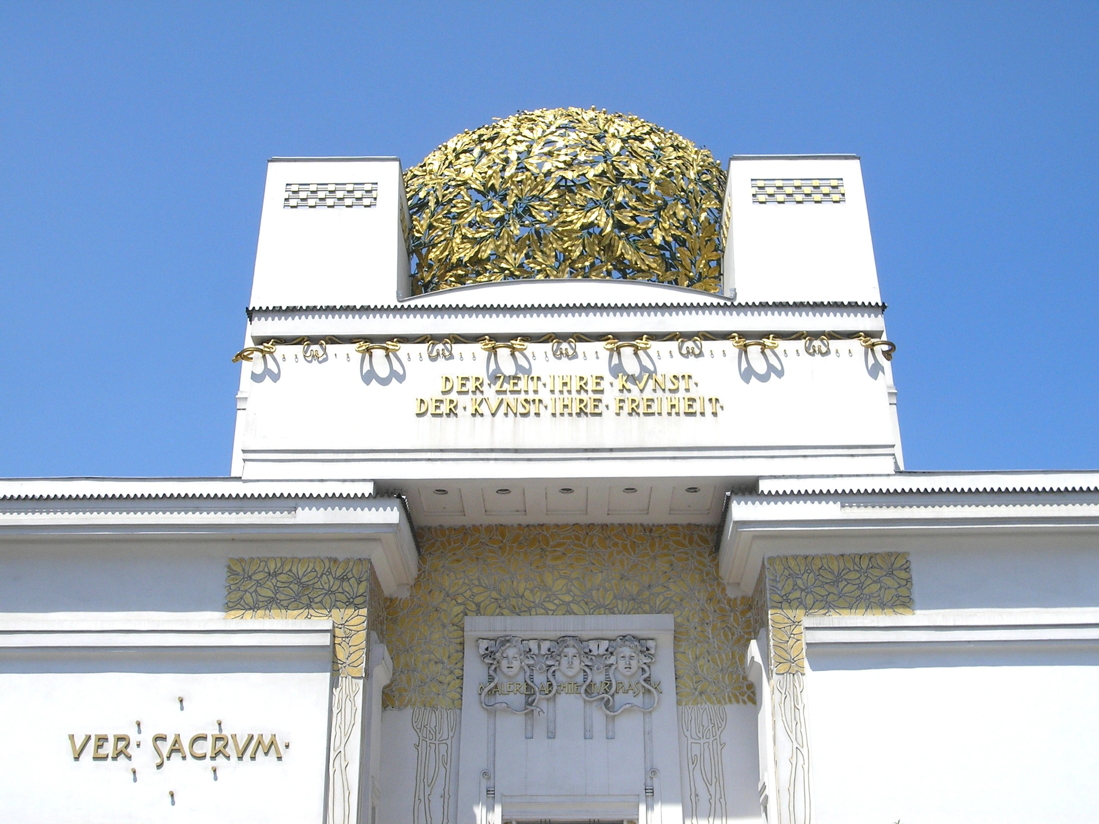 The golden dome and facade of the Vienna Secession building, featuring inscriptions and ornate details.