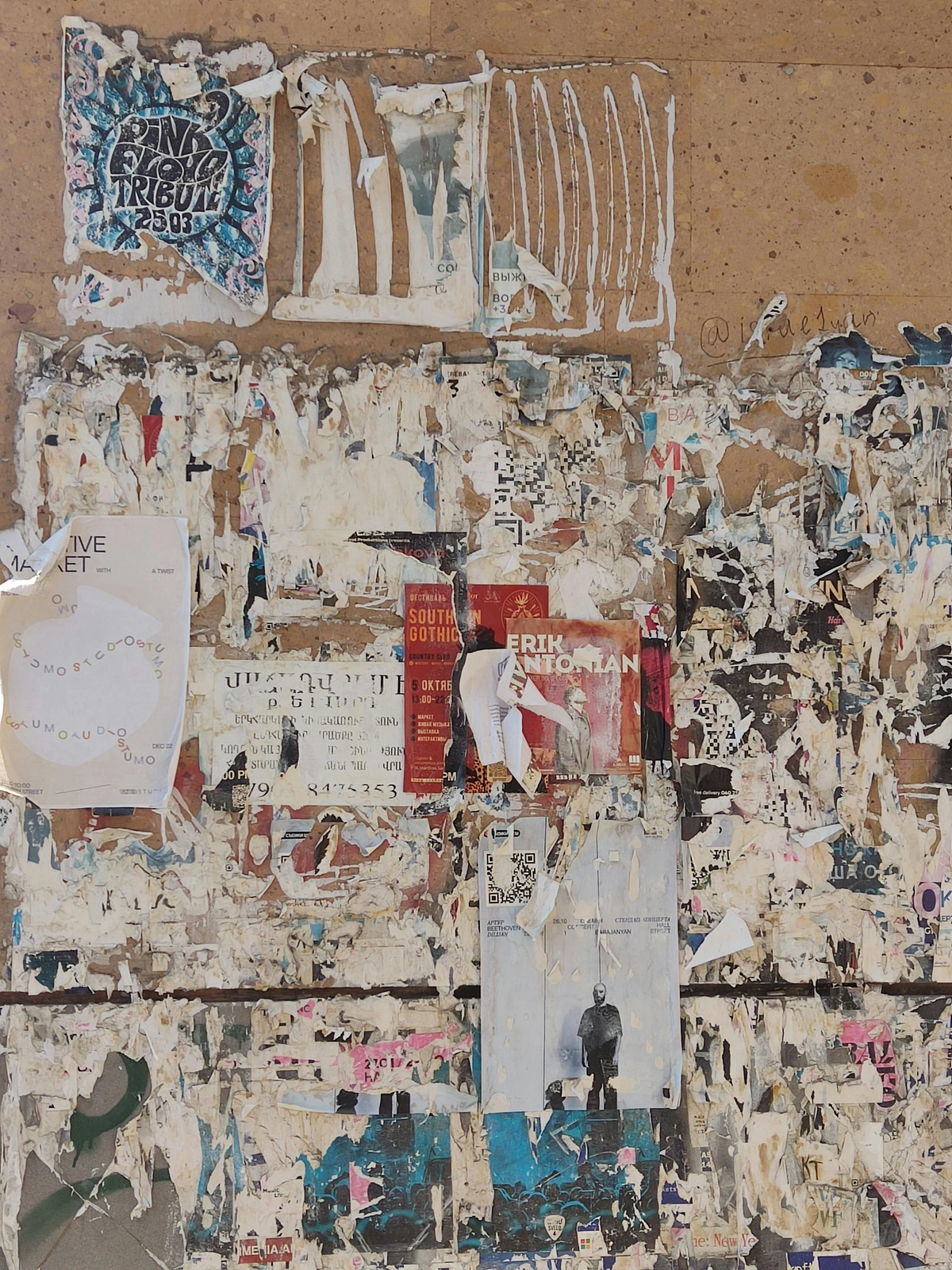 Peeling posters on a weathered bulletin board showcasing urban decay and street art aesthetics