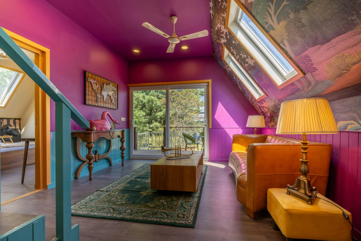 Cozy attic room with vibrant purple walls, slanted ceilings, a leather sofa, and eclectic decor.