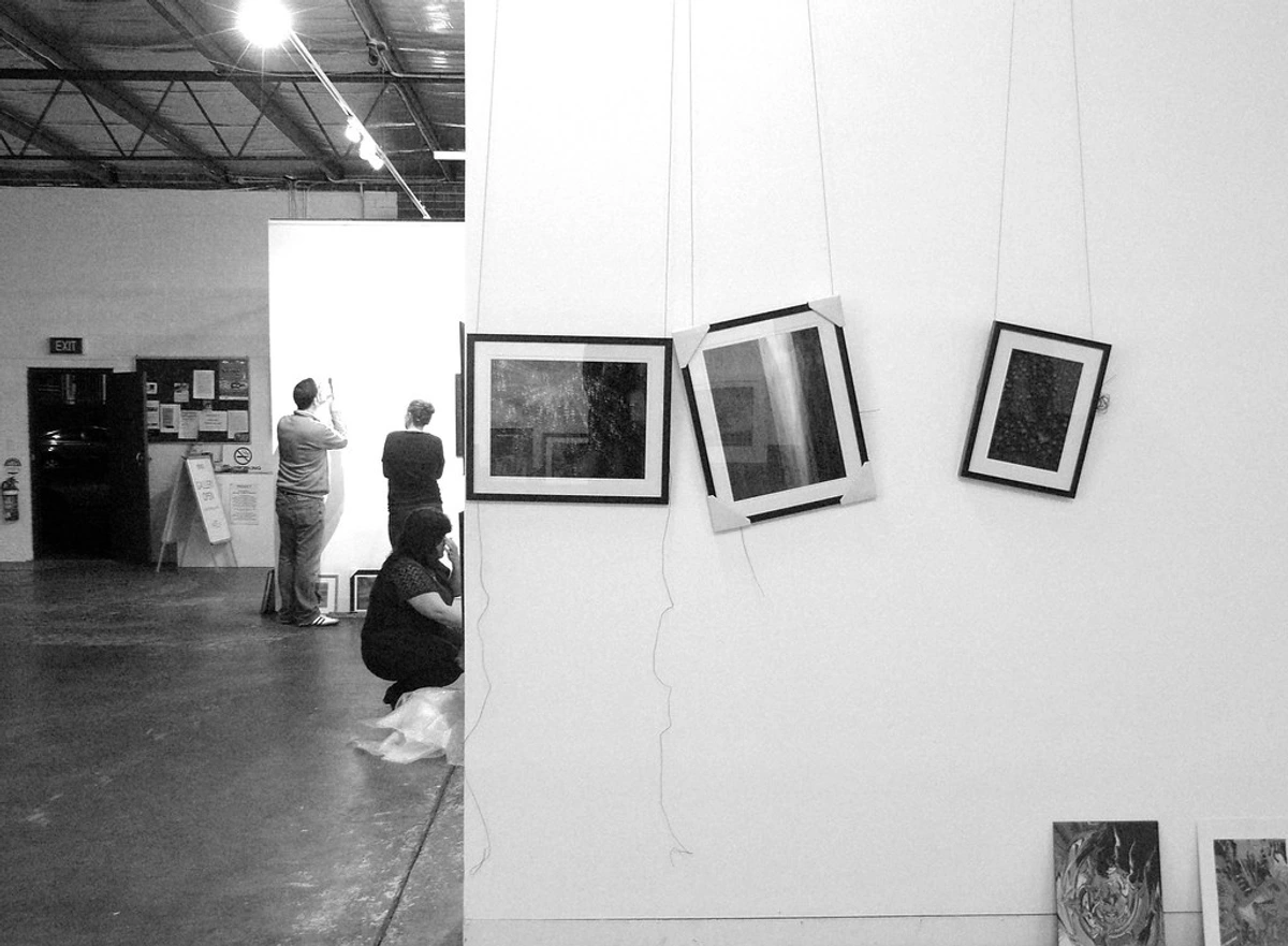 Curated artworks on display in a gallery with multiple framed pieces and exhibition context boards visible in the background.