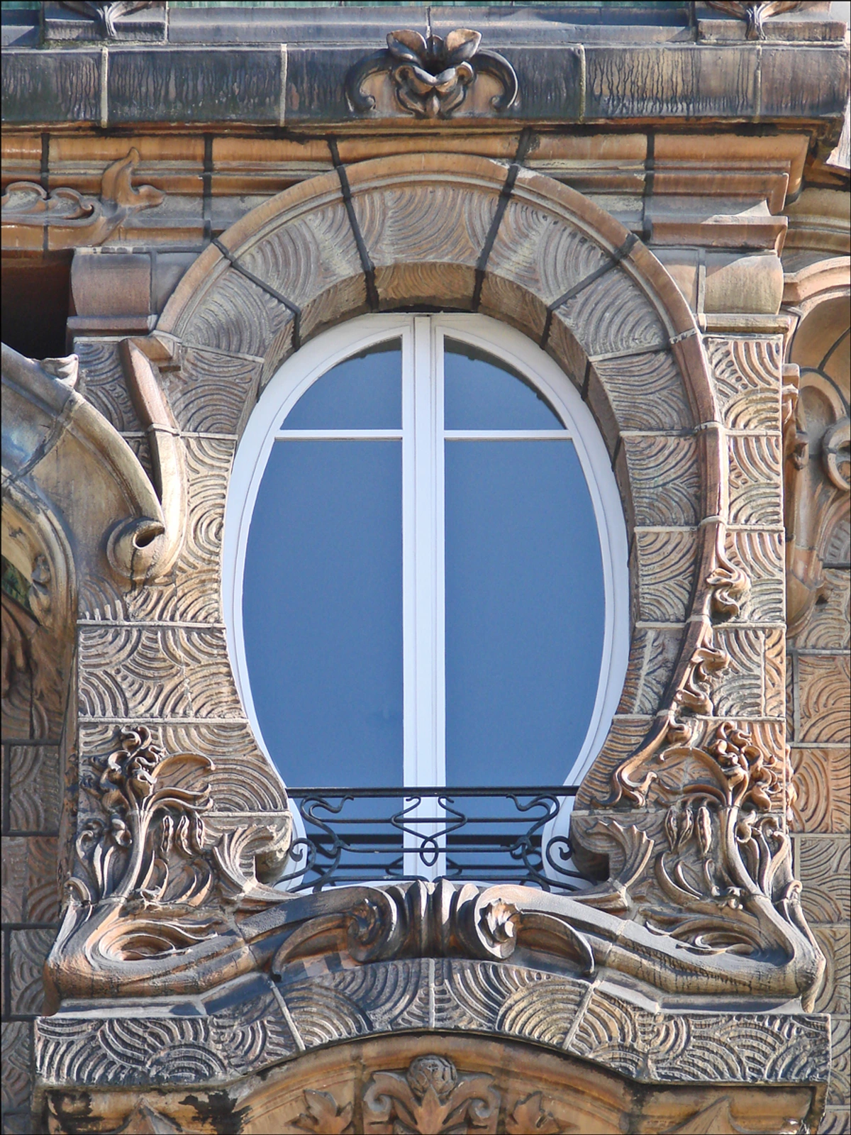 Art Nouveau building facade with an ornate oval window and decorative sculptures by Jules Lavirotte in Paris