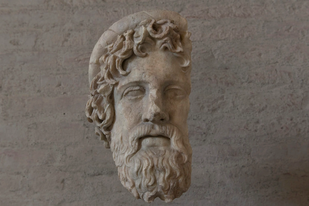 Statue of Asklepios, Greek god of medicine with bearded face and laurel wreath, marble sculpture in museum setting