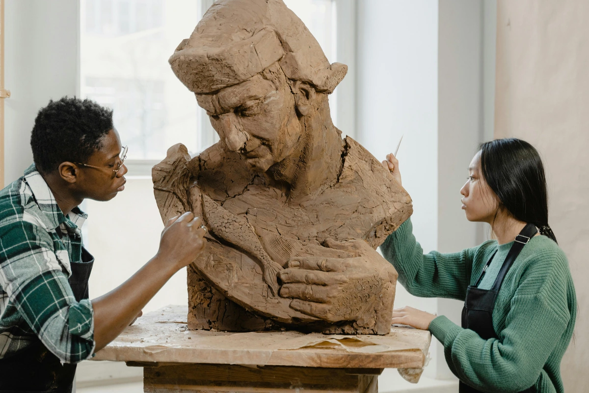 sculptors using sculpting tools on a clay statue subject, close-up of hands carving intricate details into clay sculpture, artistic collaboration in ceramics studio, high-quality stock image for artists-who-spend-countless-hours-creating theme