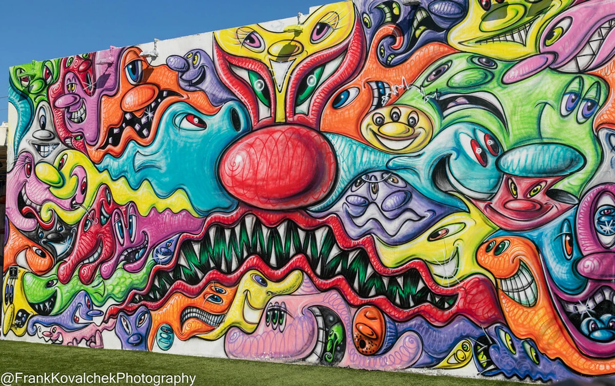Vibrant and colorful mural of cartoonish monsters with expressive faces and sharp teeth, a prominent piece of street art in Wynwood Walls, Miami.