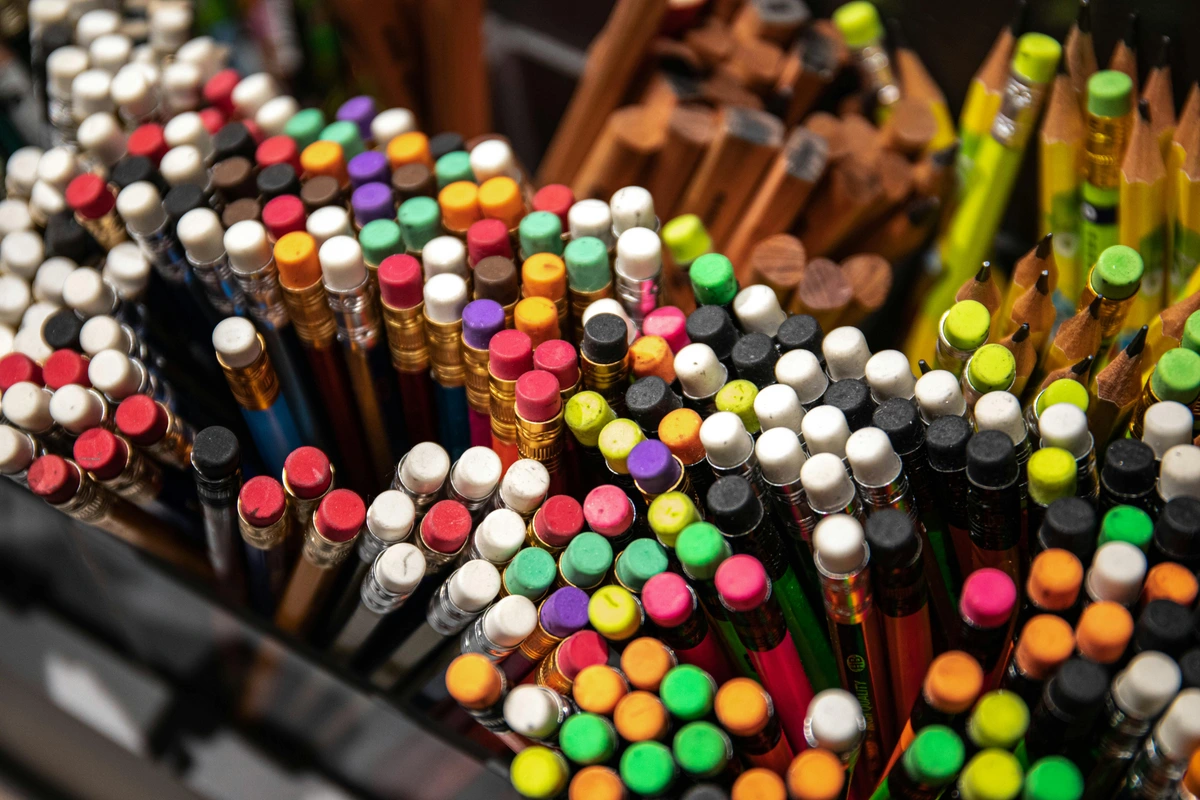 A close-up view of a variety of colored pencils with erasers in a box, showcasing a vibrant collection of art supplies.