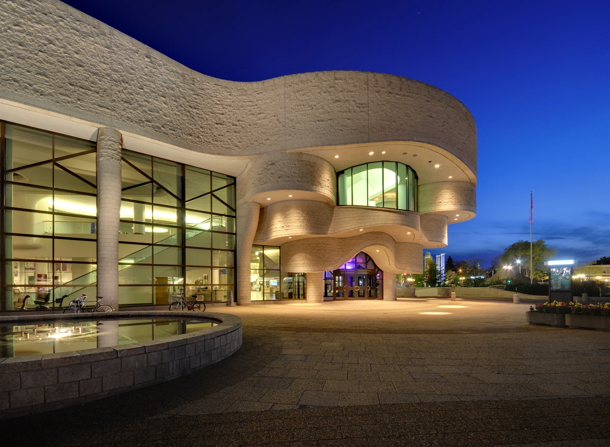 The Canadian Museum of History in Gatineau, Quebec, at dusk, showcasing its distinctive modern architecture with curved stone and glass facades.