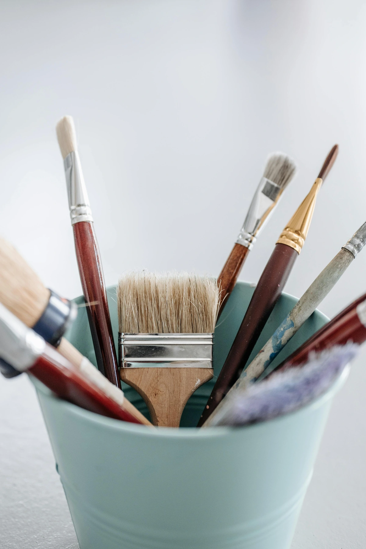Synthetic paint brushes in blue container holder with rich bristle variety