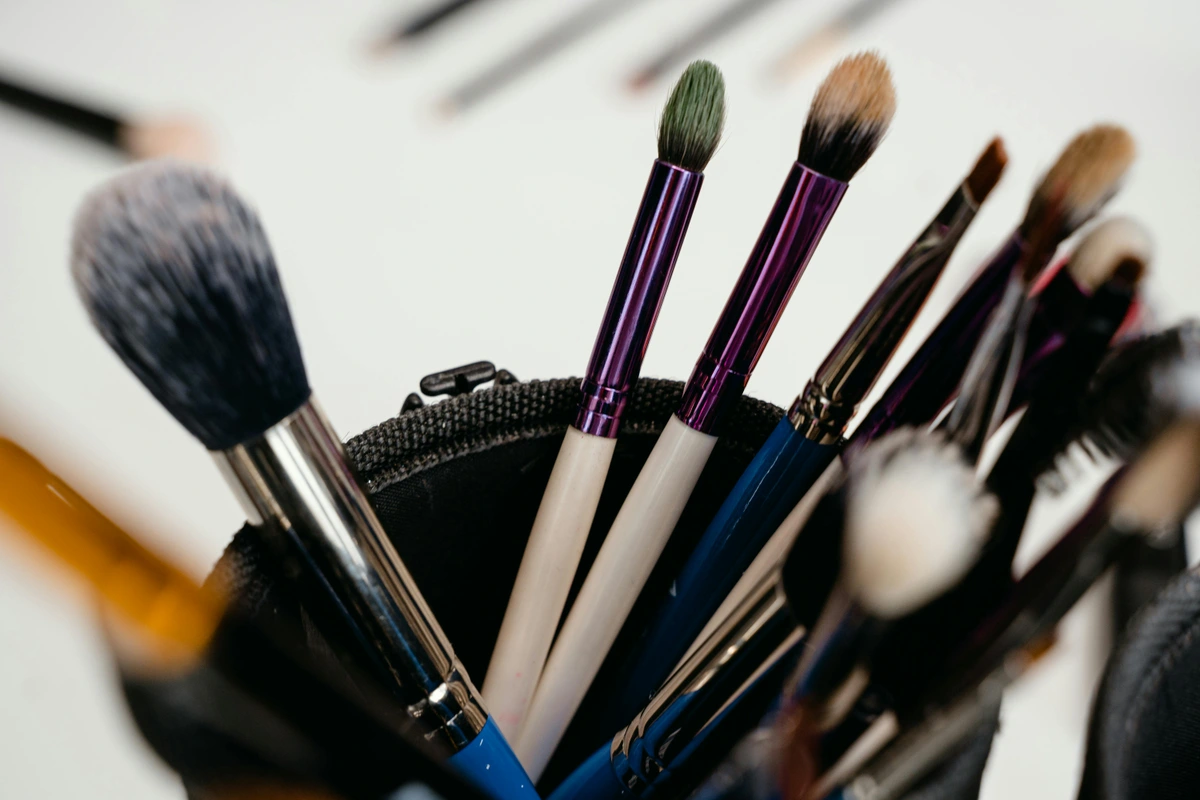 Assorted synthetic makeup brushes in a black holder with purple and black handles, ideal for product reviews and beauty tutorials.