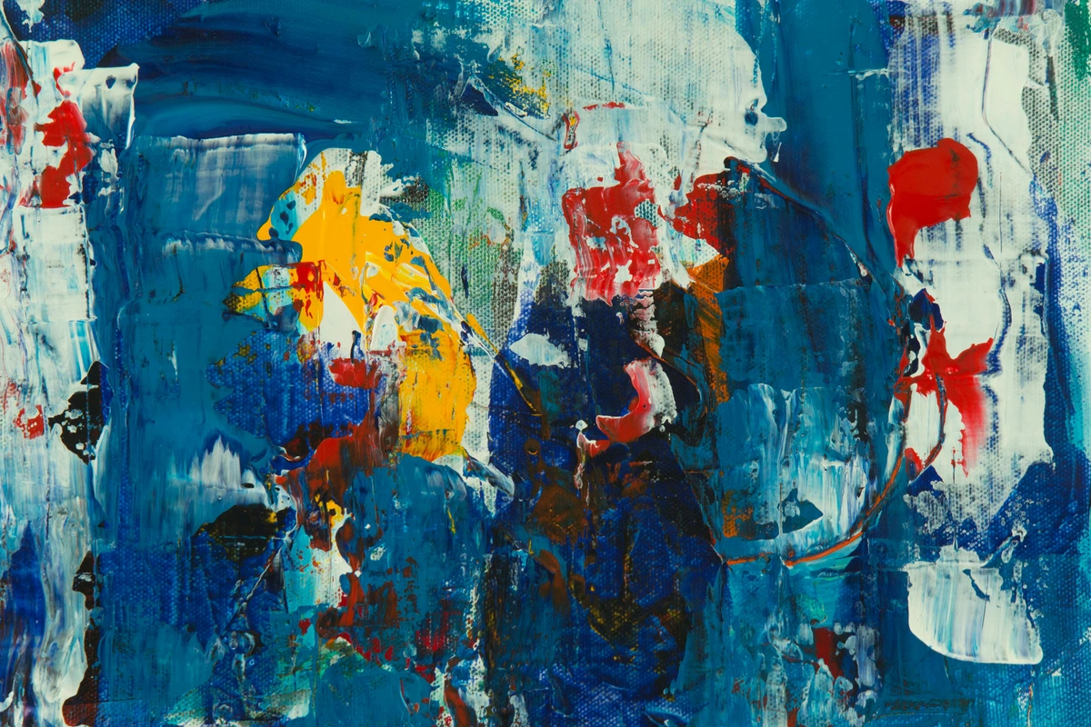 Close-up photo of an abstract painting with thick impasto strokes in blue, yellow, and red, showcasing texture and vibrant colors