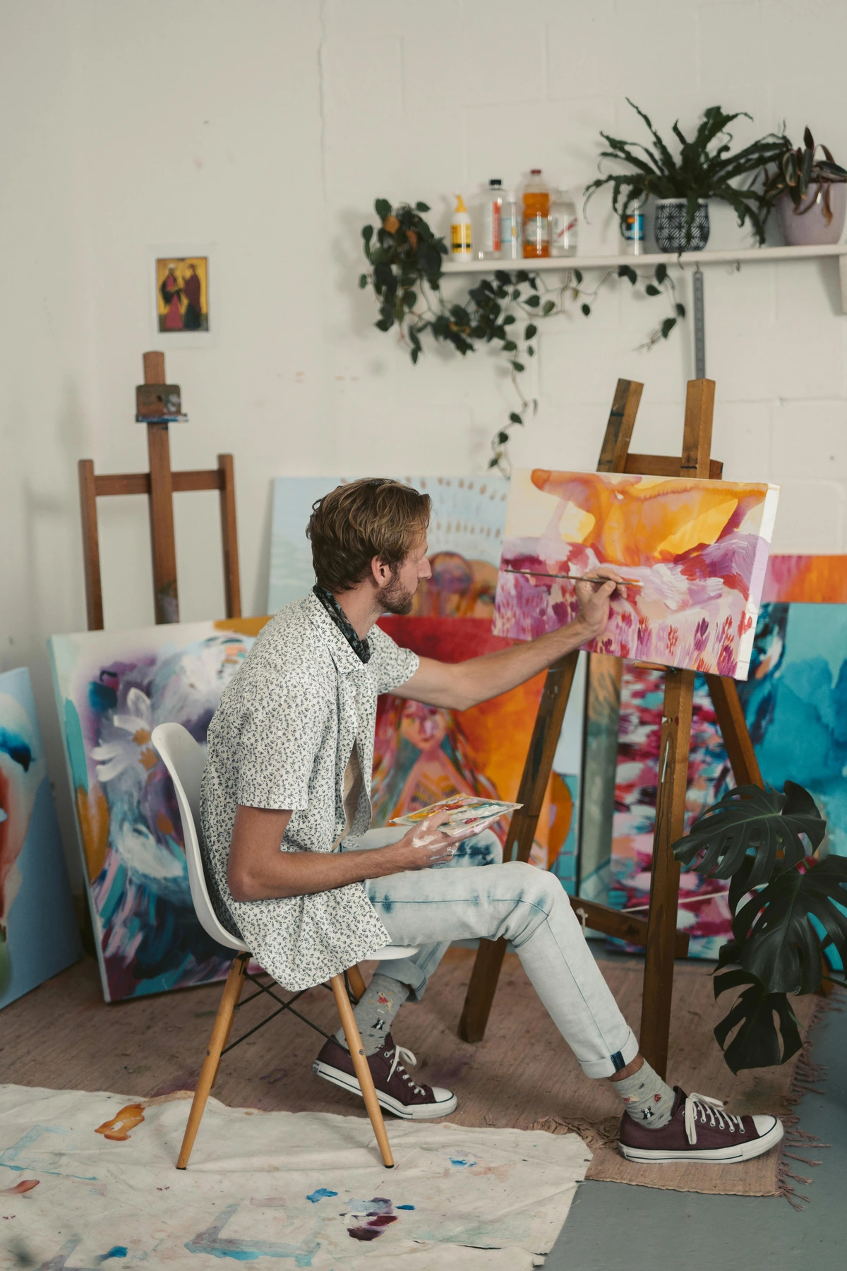 A bearded man painting a custom artwork in a studio