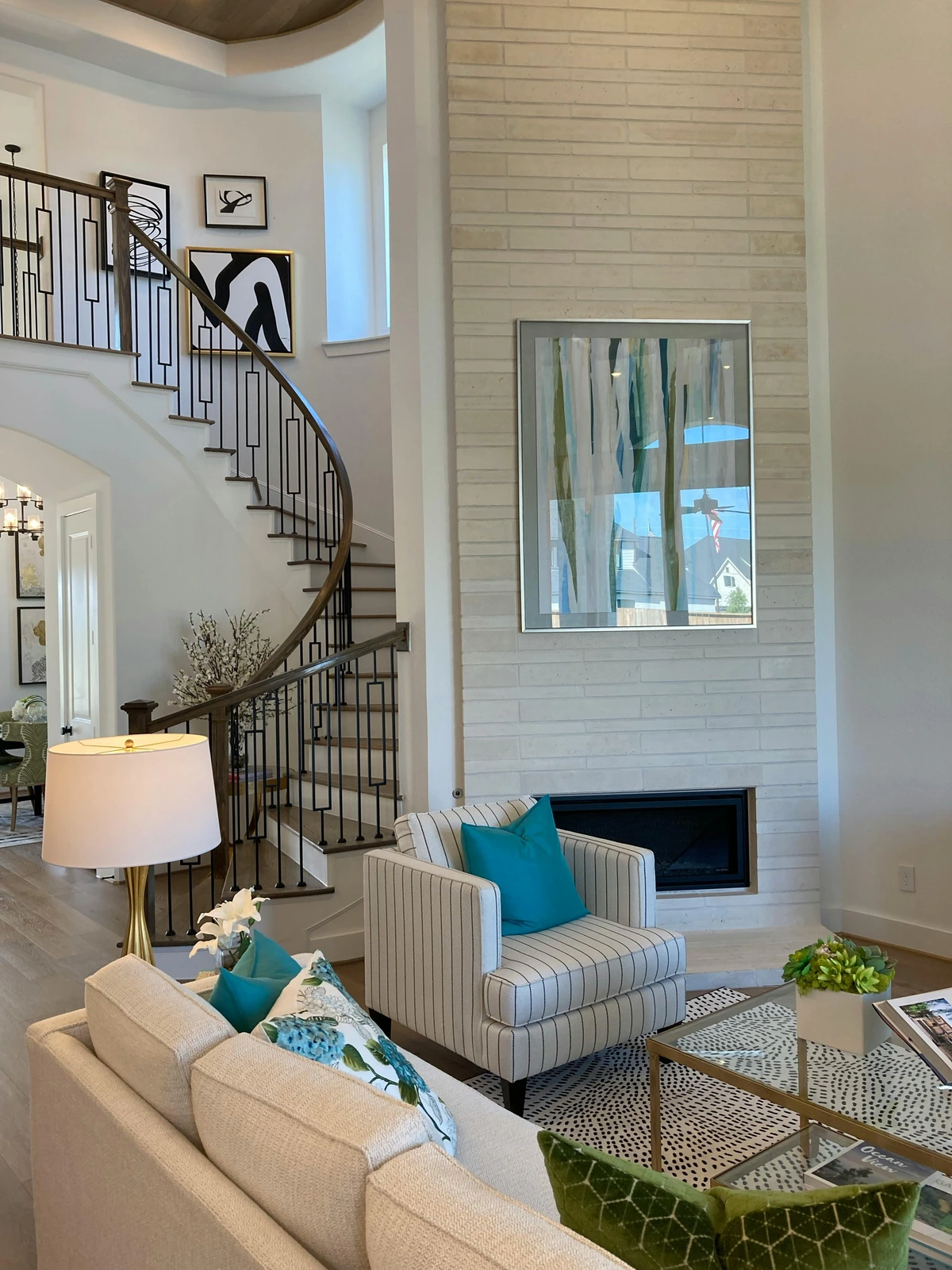 Interior of a modern living room featuring a large spiral staircase, a fireplace with abstract art above it, and contemporary furniture.