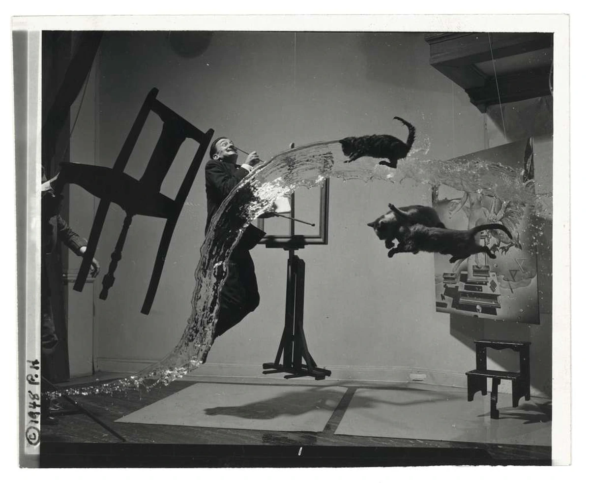 Salvador Dalí A (Dali Atomicus) 09633u original - A surreal scene of a man balancing on a desk with cats floating in water arcs