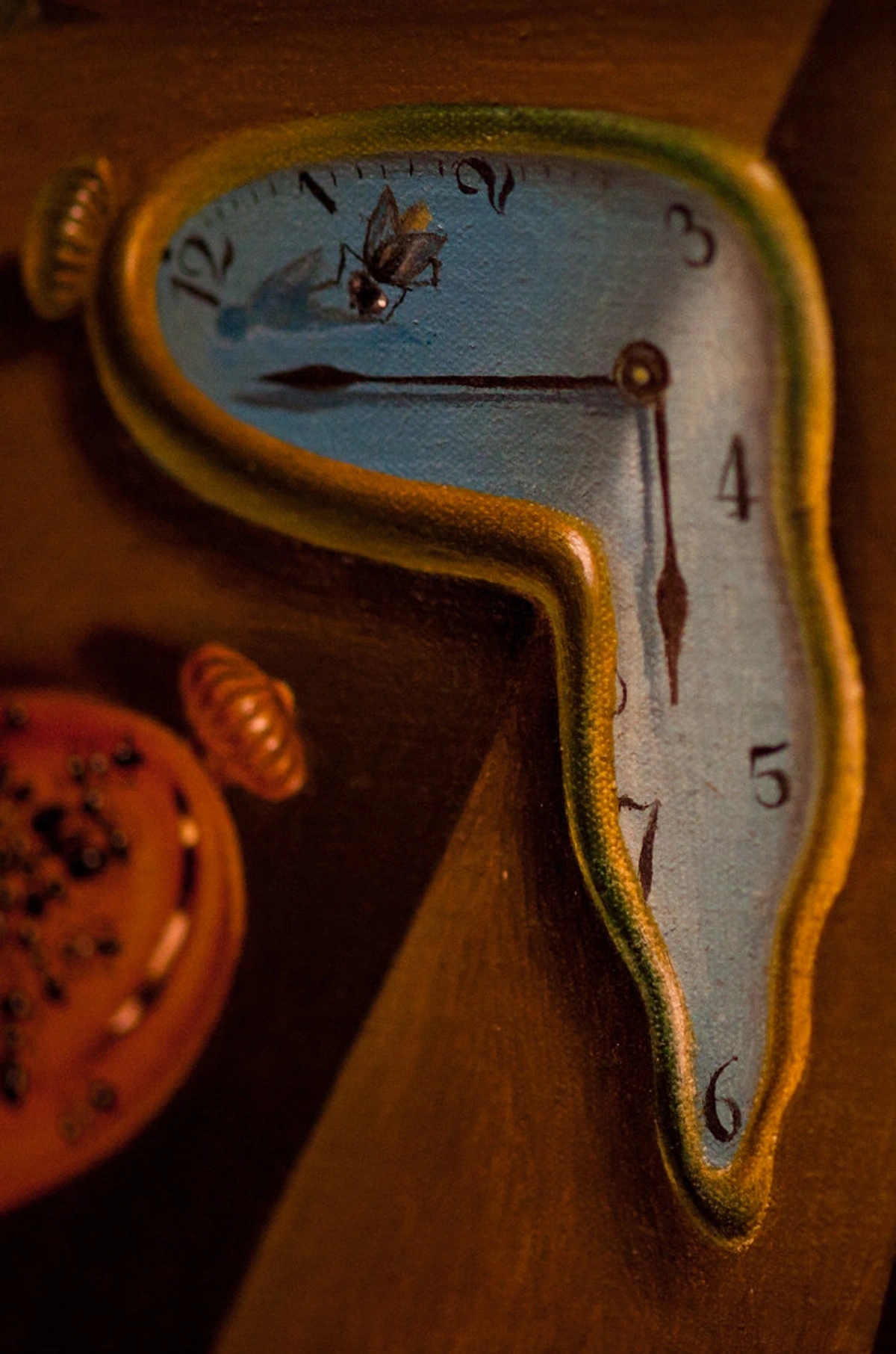 Close-up of Salvador Dalí's painting 'The Persistence of Memory' with melting clock and fly, symbolizing surrealism's enduring appeal.