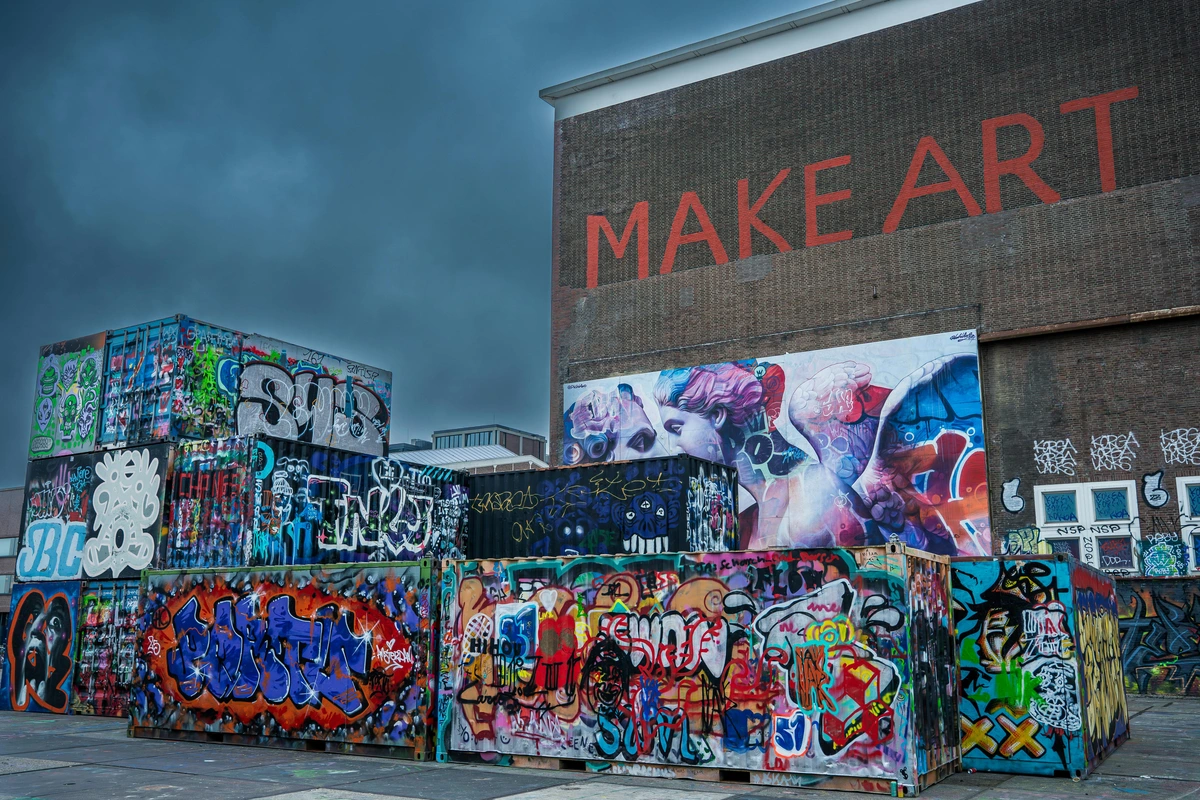 Colorful urban graffiti art on shipping containers and a building wall with 'Make Art' written in red.