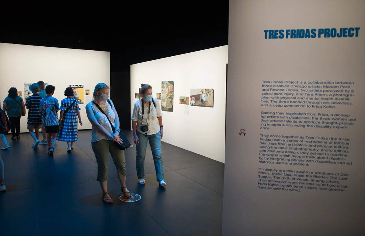 Bezoekers met mondkapjes bekijken kunst op de Tres Fridas Project-tentoonstelling, geïnspireerd op Frida Kahlo.