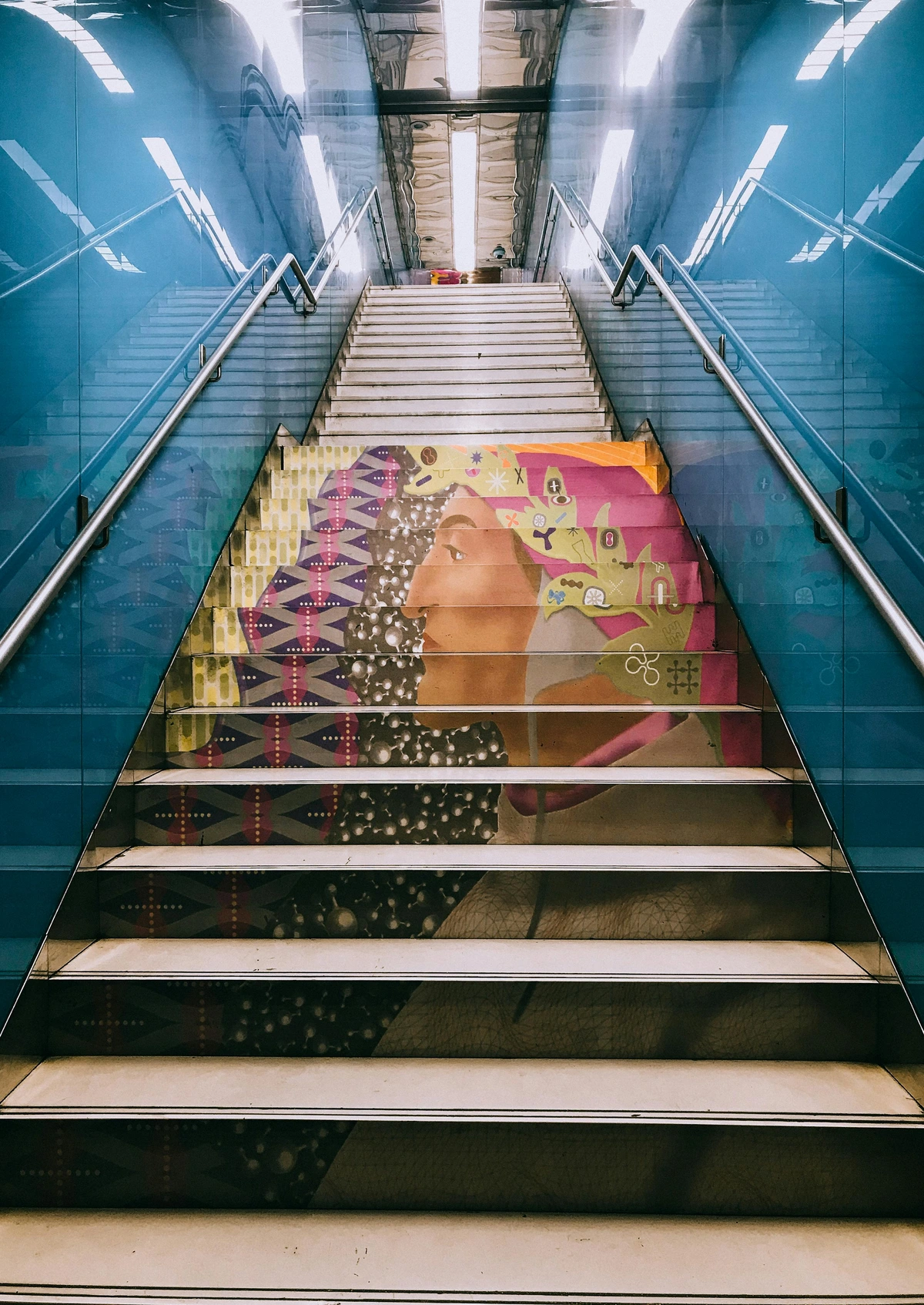 Colorful staircase art featuring a woman's profile and geometric patterns in a subway station
