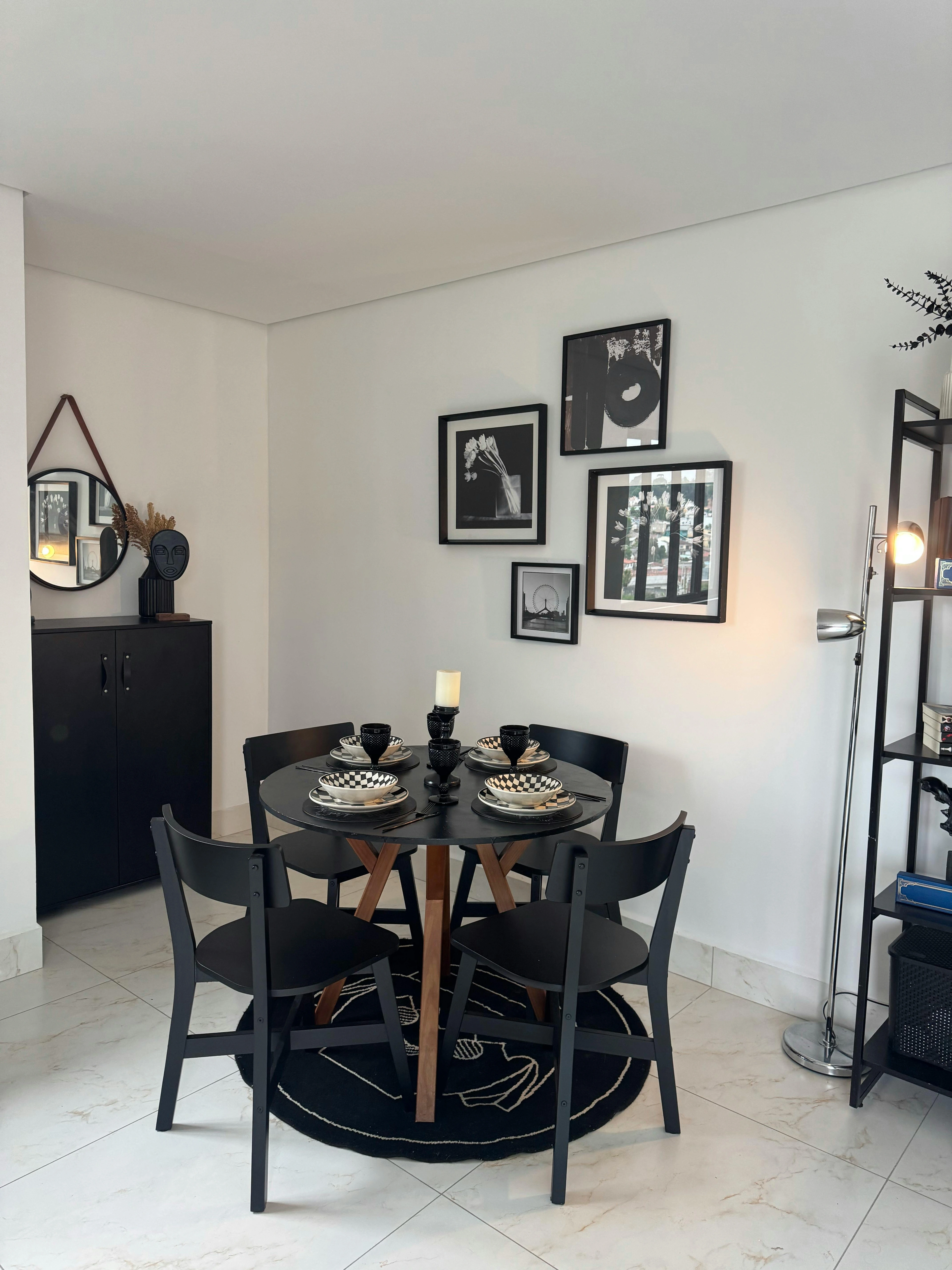 Modern dining room with a round black table, black chairs, and black and white wall art.