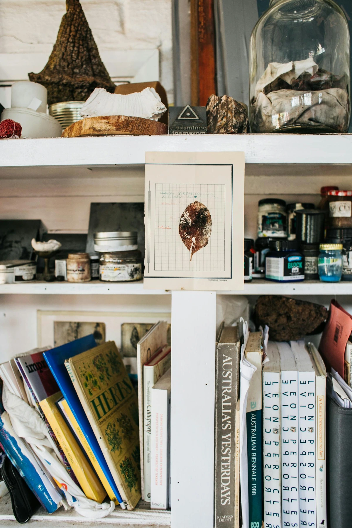 A rustic wooden bookshelf filled with a variety of books, jars, and decorative items, showcasing a unique way to display art and collectibles.