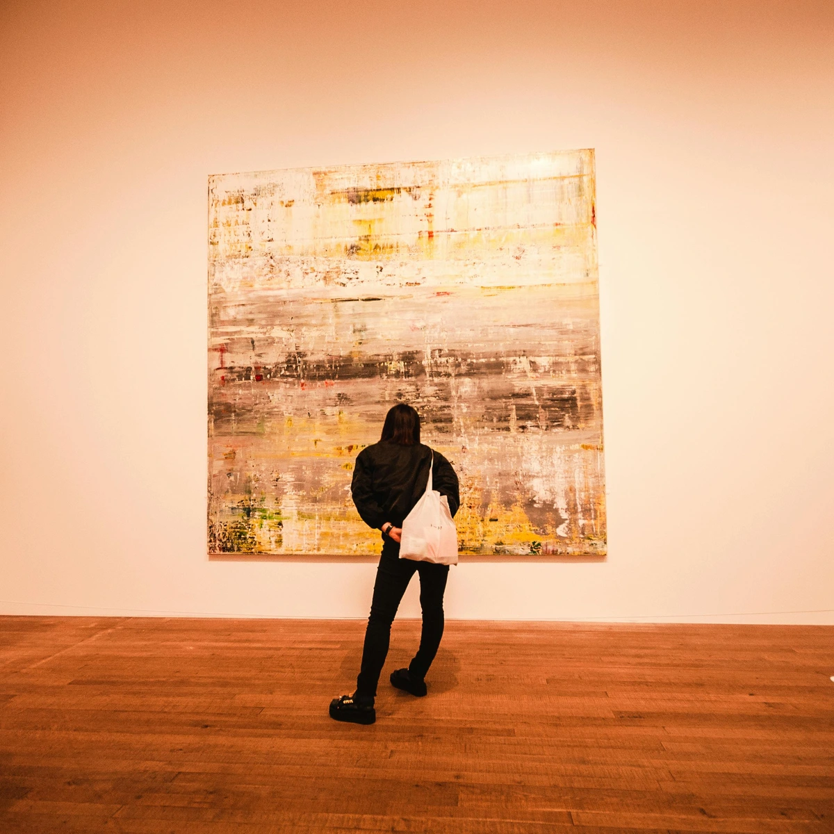 Woman studying abstract painting in gallery exhibiting art analysis concept consumer shopping bag