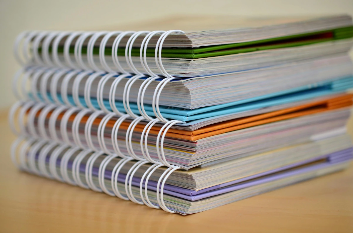 Stack of colorful spiral-bound notebooks on a wooden table