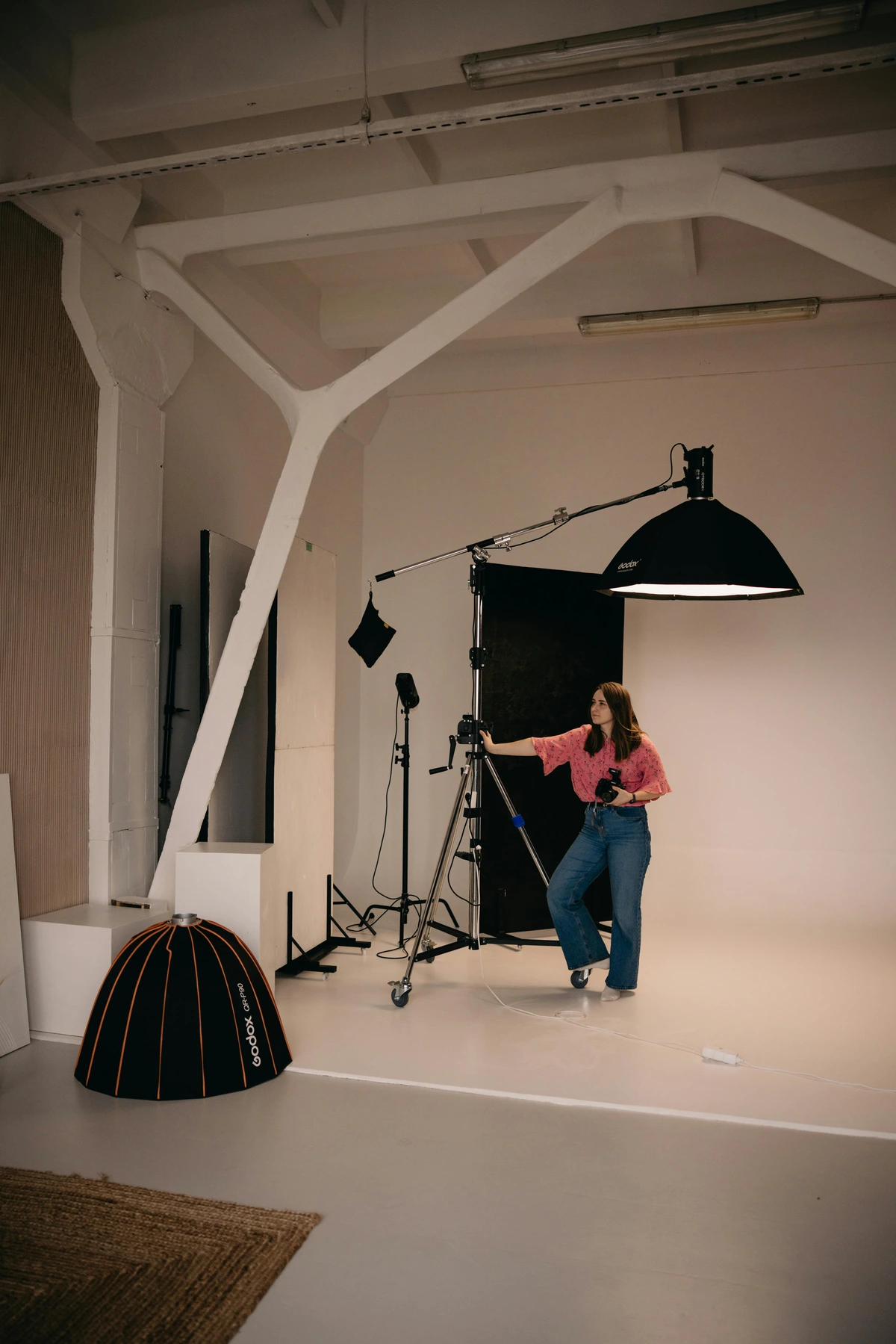 A female photographer adjusts lighting equipment in a studio, preparing to photograph art.