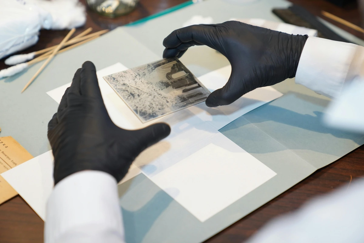 A Photograph Restoration Specialist carefully mounting and archiving historical photos in acid-free boxes for long-term preservation.