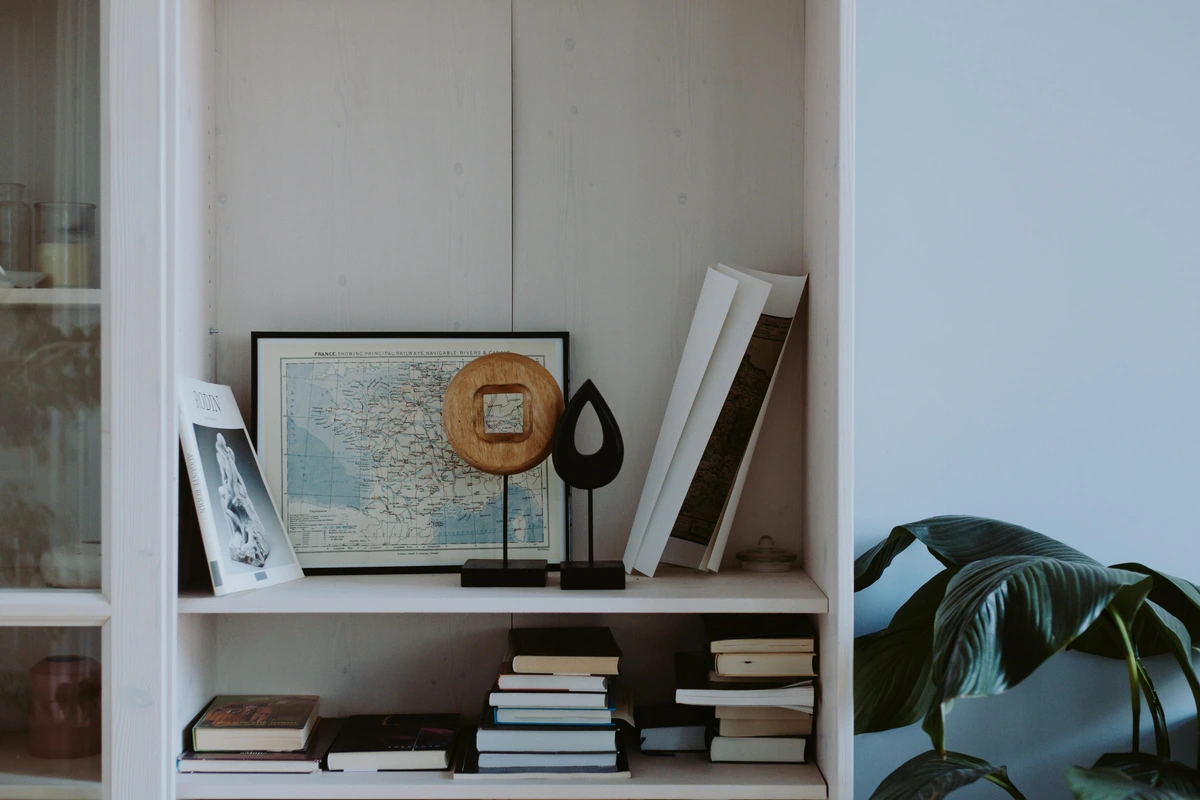 Books, a framed map of France, and decorative objects artfully arranged on a white bookshelf.