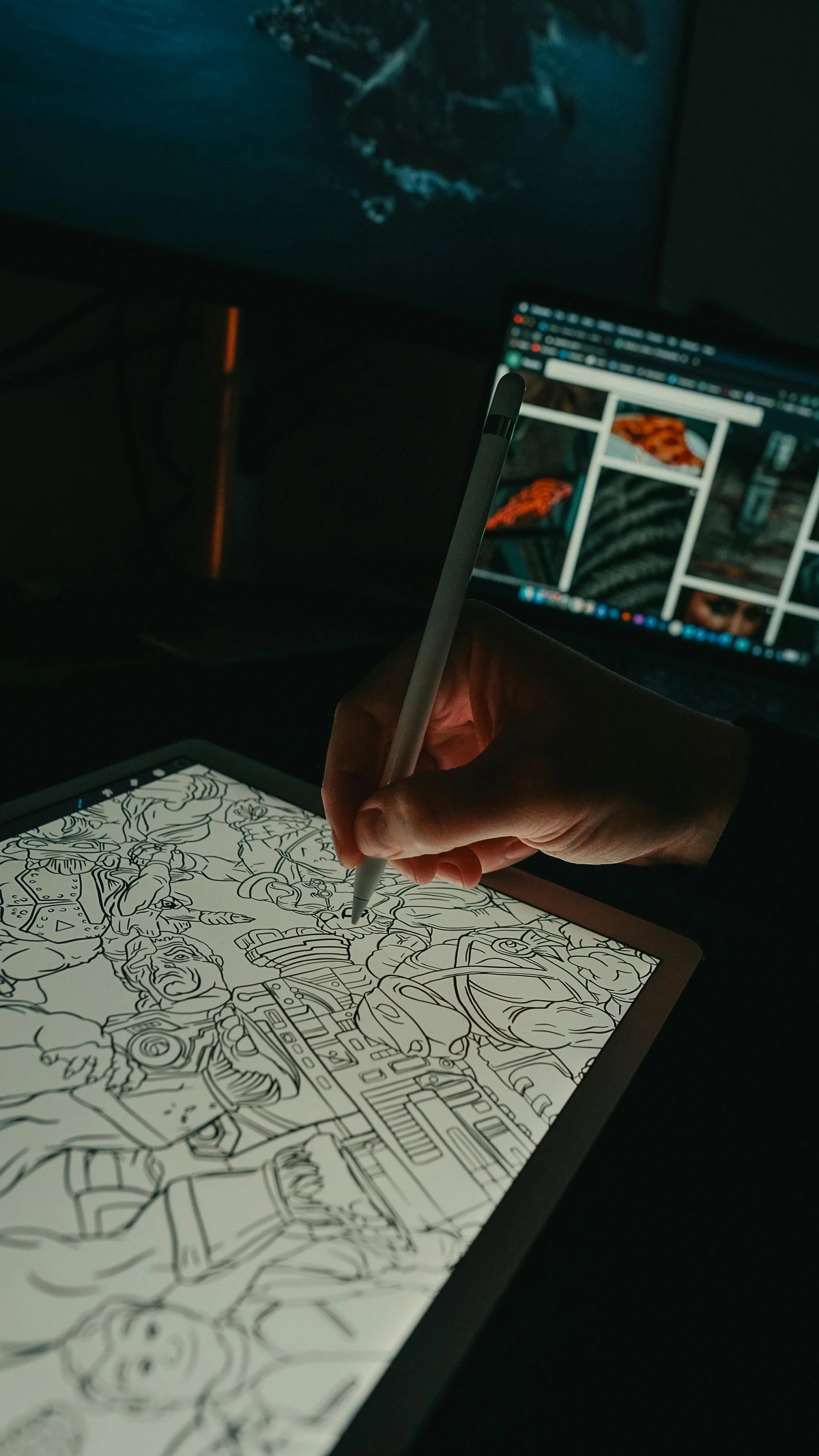 Hand using an Apple Pencil to draw on an iPad screen, with a laptop in the background displaying images.