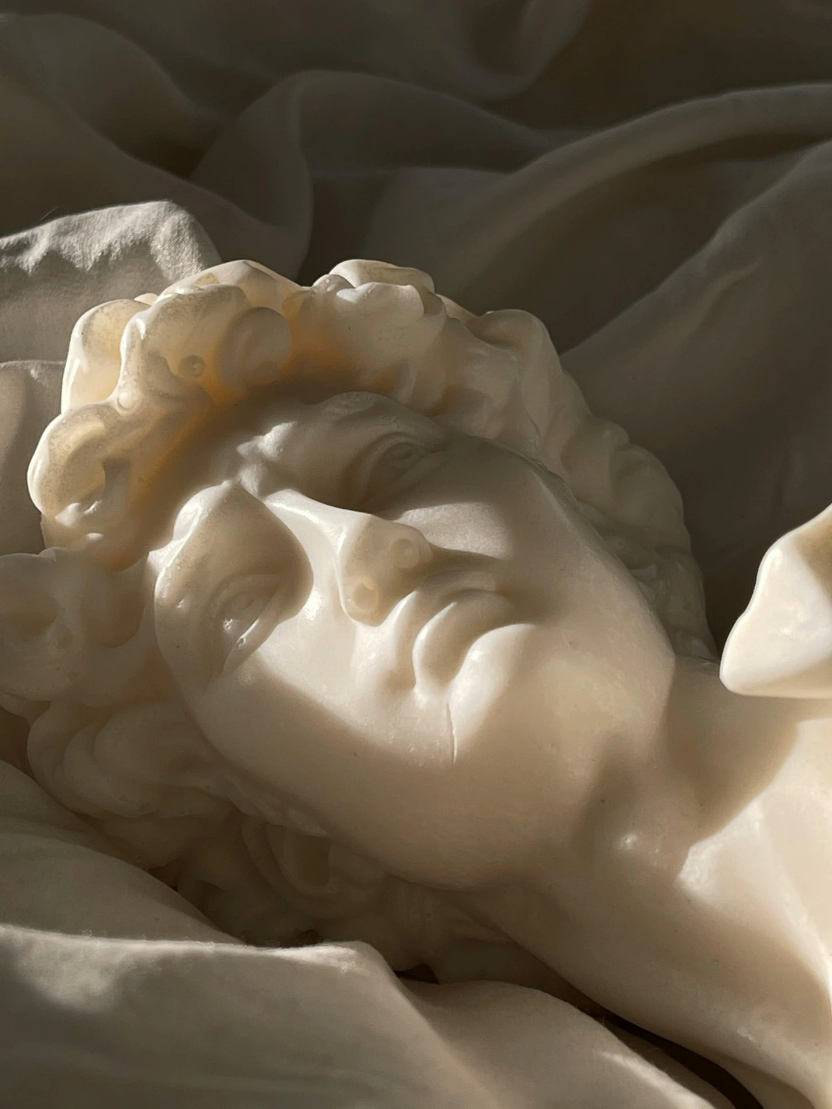 Dramatic lighting highlights the intricate details of a marble face sculpture, showcasing art quality and craftsmanship.