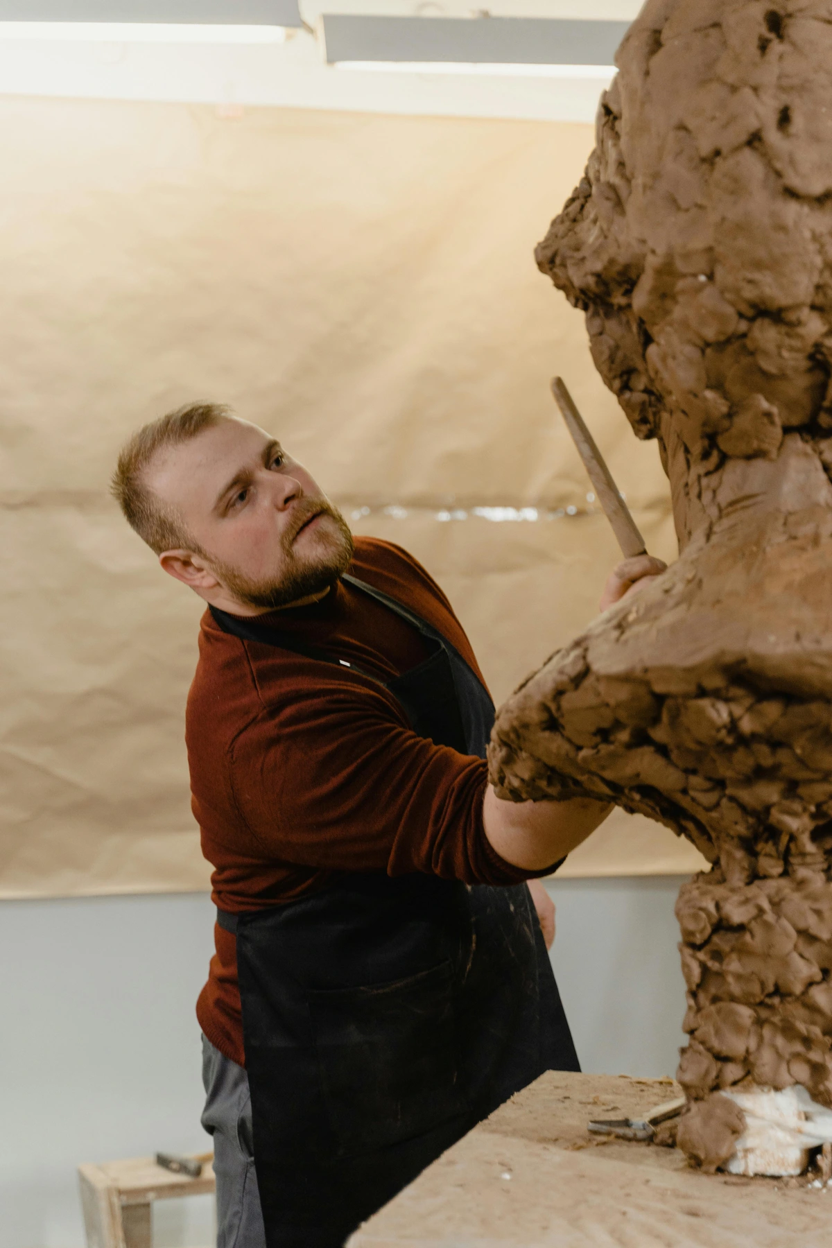 sculptor crafting clay sculpture with meticulous precision in studio setting, capturing artistic process and dedication
