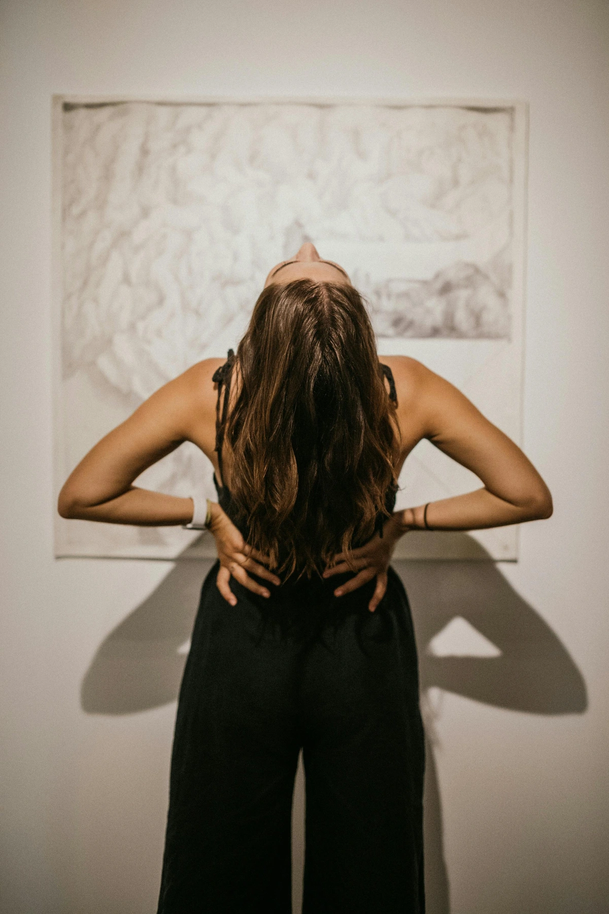 Woman in black clothes leaning back against abstract art background, confident pose, free stock photo