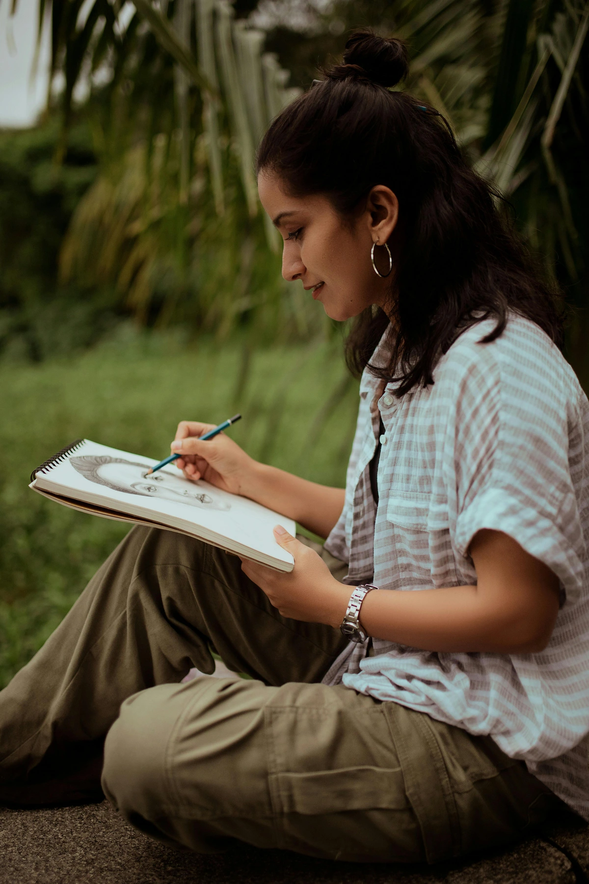 Artist exploring creative ideas outdoors while sketching and taking notes in a natural setting.