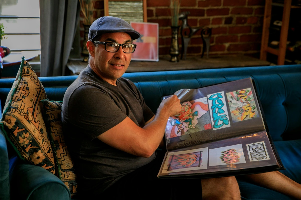 A man showcasing his art portfolio with long-term career strategies for artists. Free stock photo of a creative professional presenting his work.