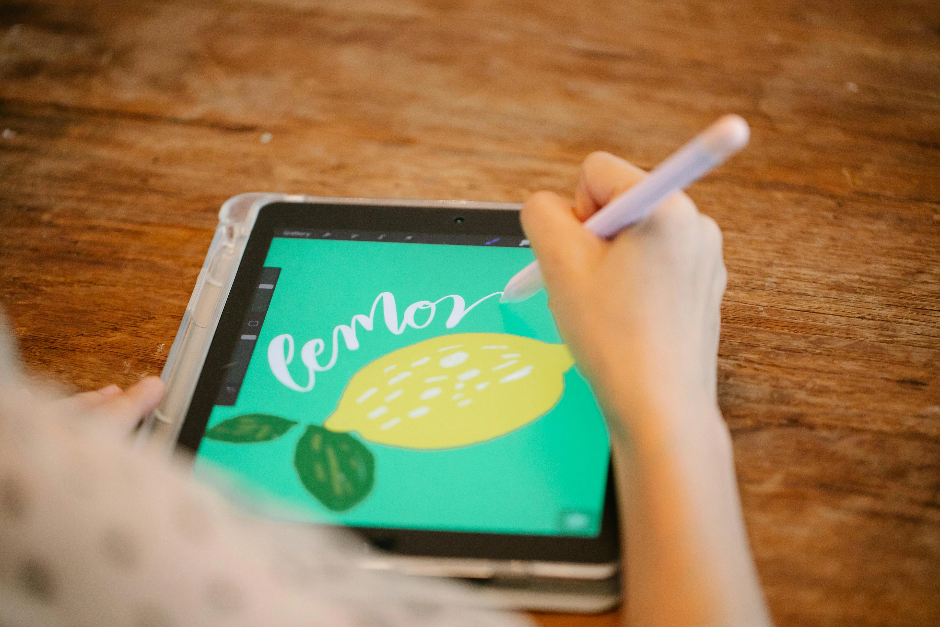 Woman drawing a digital lemon illustration on a tablet, demonstrating beginner-friendly digital art techniques with a teal background and simple graphics