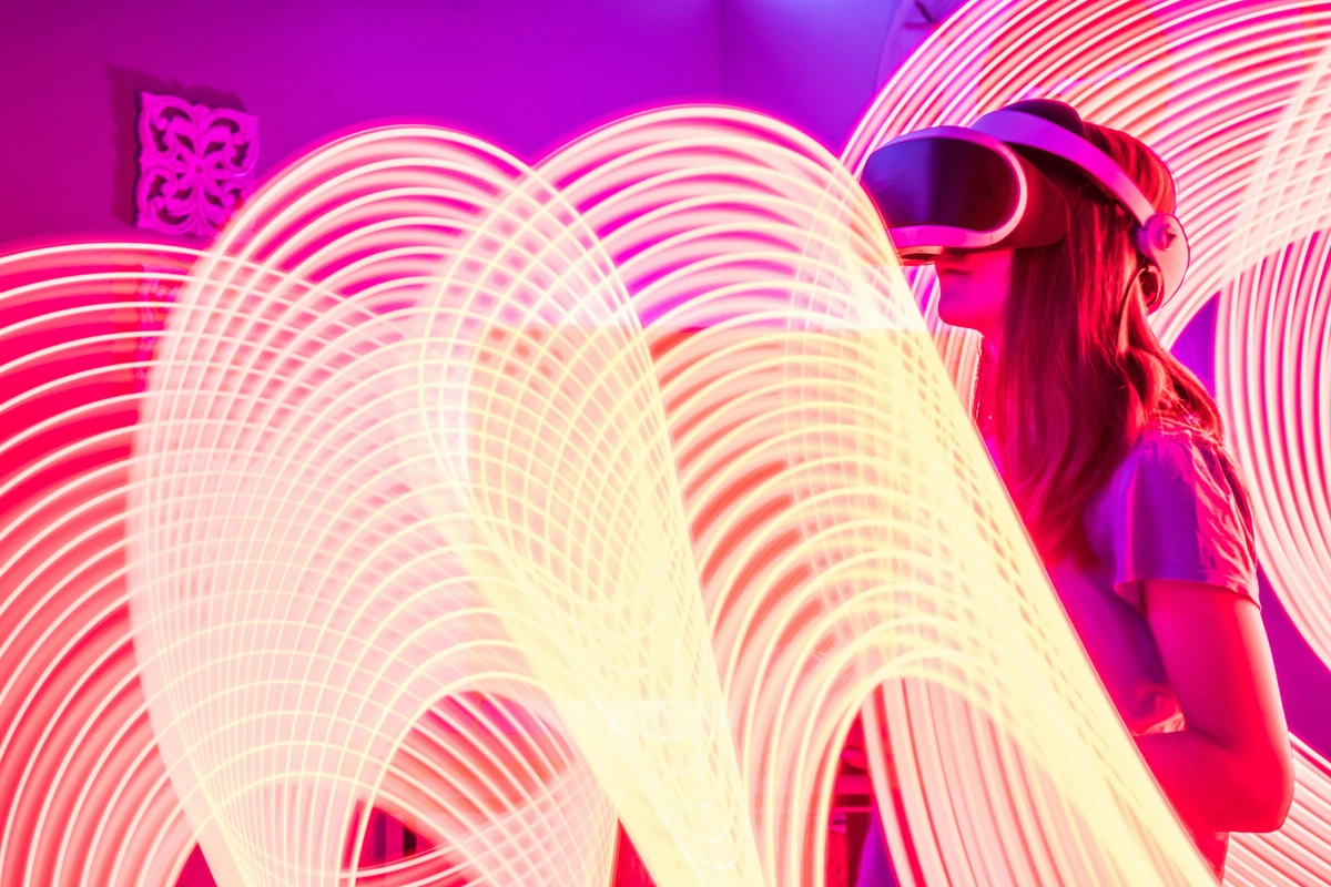 A woman wearing VR goggles amidst dynamic digital light trails, symbolizing emerging art-technology fusion in immersive exploration contexts. AR, virtual reality, digital innovation art.