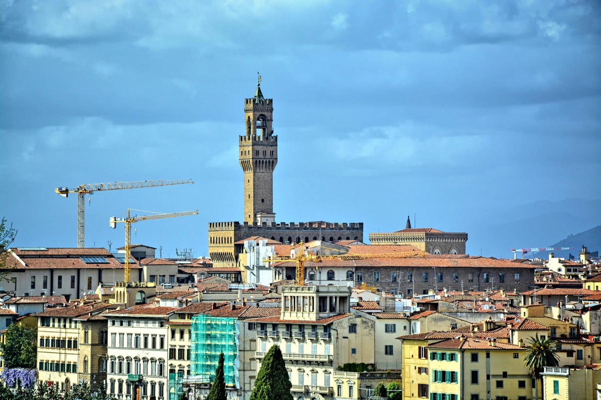 The Palazzo Vecchio Tower in Florence, Italy, surrounded by historic buildings and a clear sky, a free stock photo for web use.