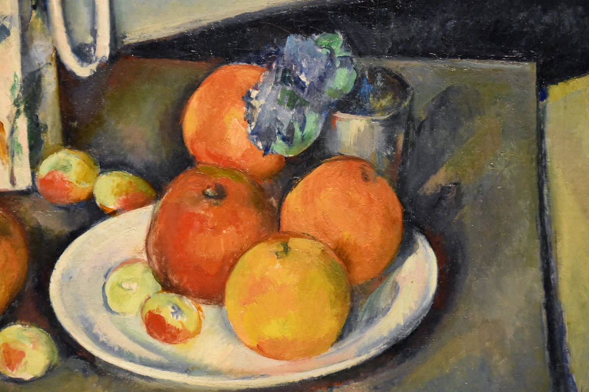 Paul Cézanne still life painting featuring oranges and apples on a white plate, with a textured background.