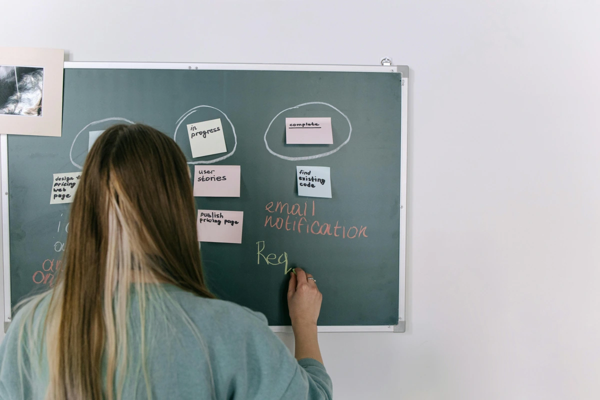 Woman writing on a blackboard with sticky notes for planning and brainstorming