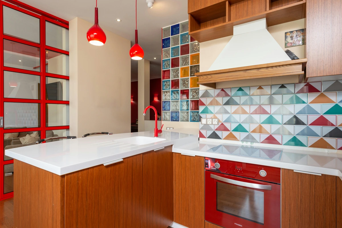 Stylish modern kitchen with colorful geometric backsplash tiles and red accents