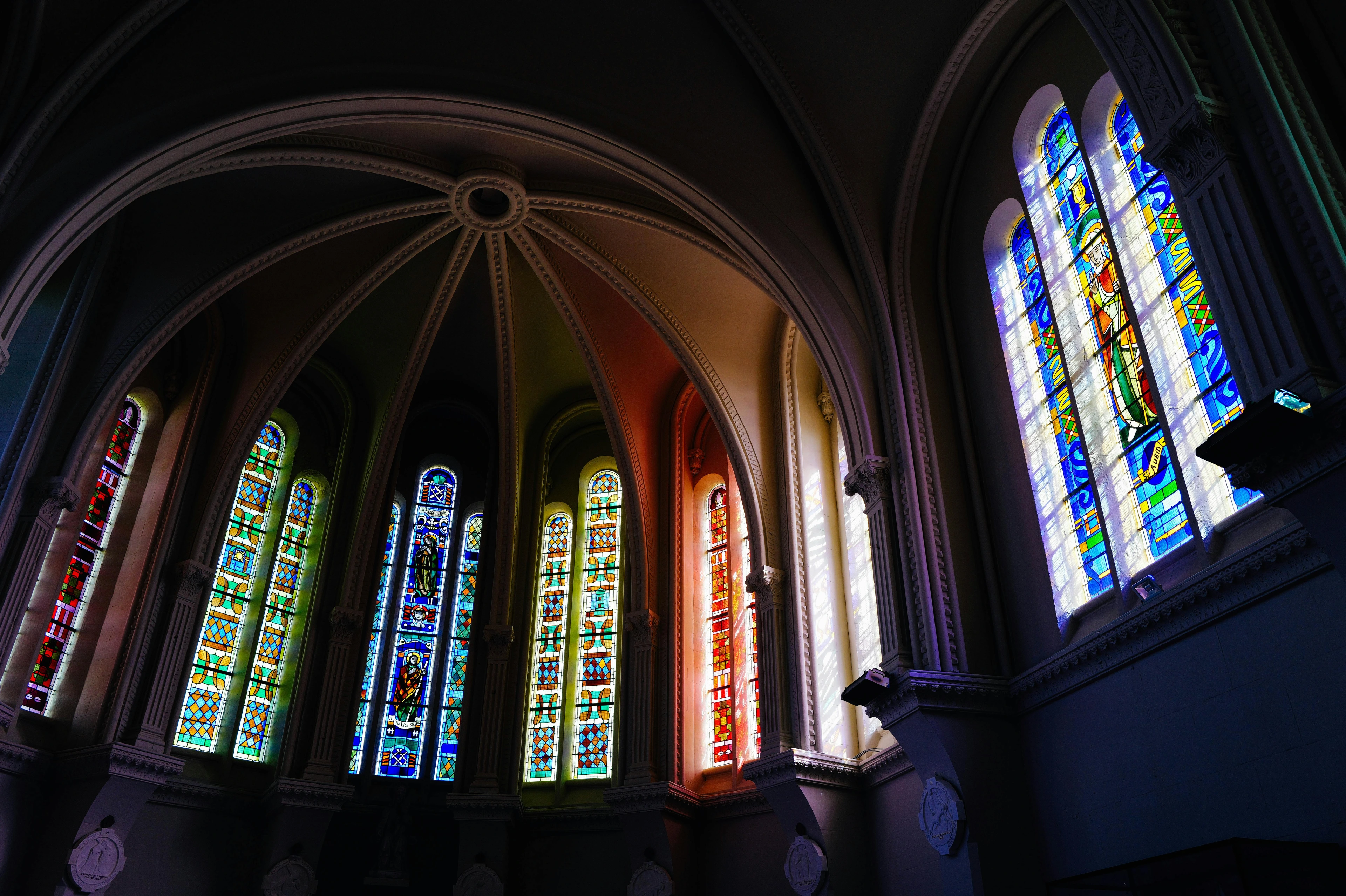 Interior view of gothic cathedral stained glass windows, showcasing intricate designs and vibrant colors filtering through the glass.