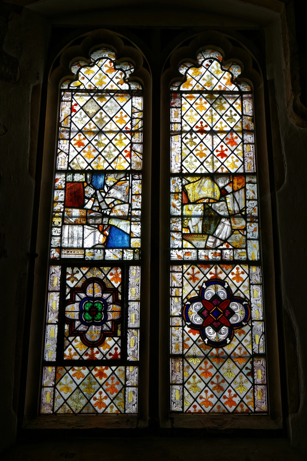 Gothic stained glass window in All Saints Church, West Stourmouth, Kent, England, featuring intricate patterns and historical depictions.