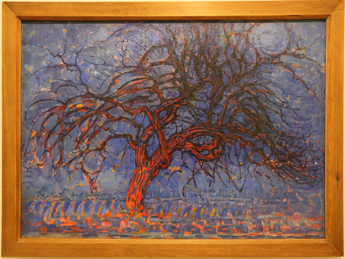 Piet Mondrian's painting 'The Red Tree' from 1908-1910, depicting a bare tree with vibrant red branches against a dark blue sky.