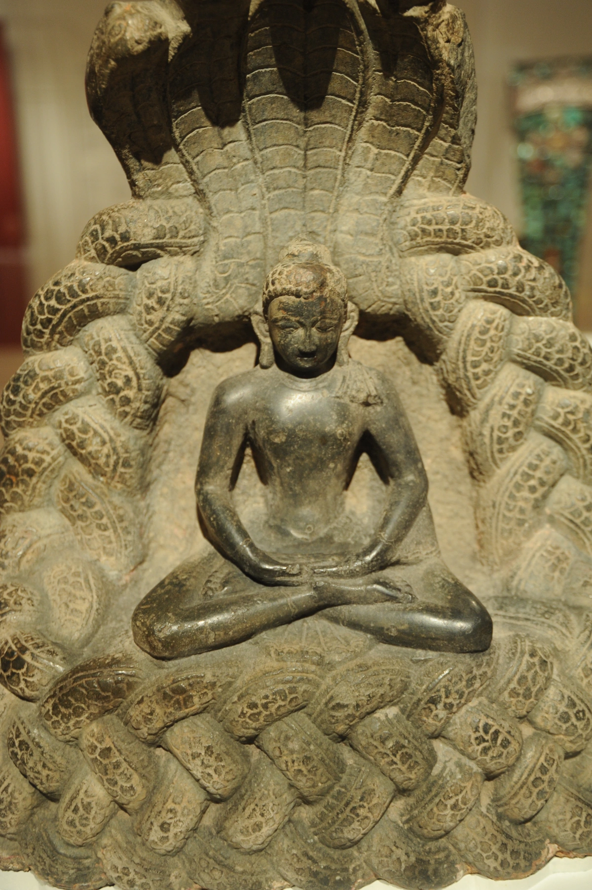 Stone sculpture of Buddha meditating under a multi-headed serpent canopy, symbolizing protection and enlightenment.